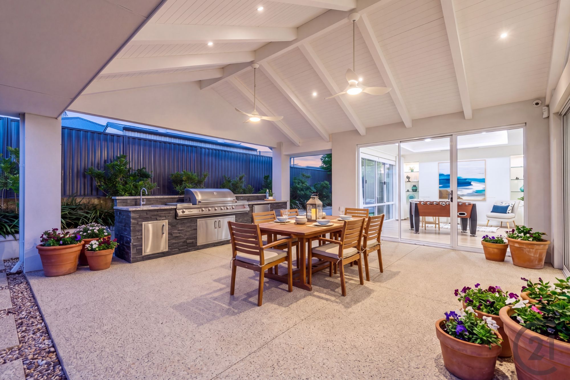 Covered alfresco with built-in barbecue, outdoor dining setting and glass doors to the games room