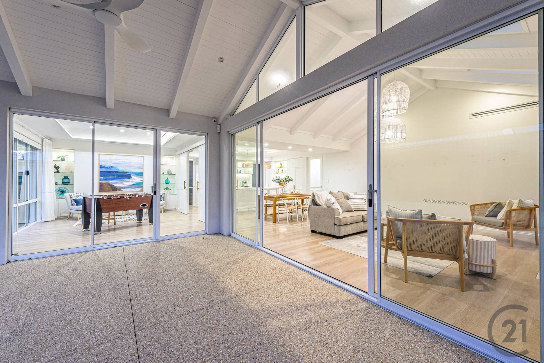 Covered alfresco under a lined, raked ceiling with glass doors to the living area and games room