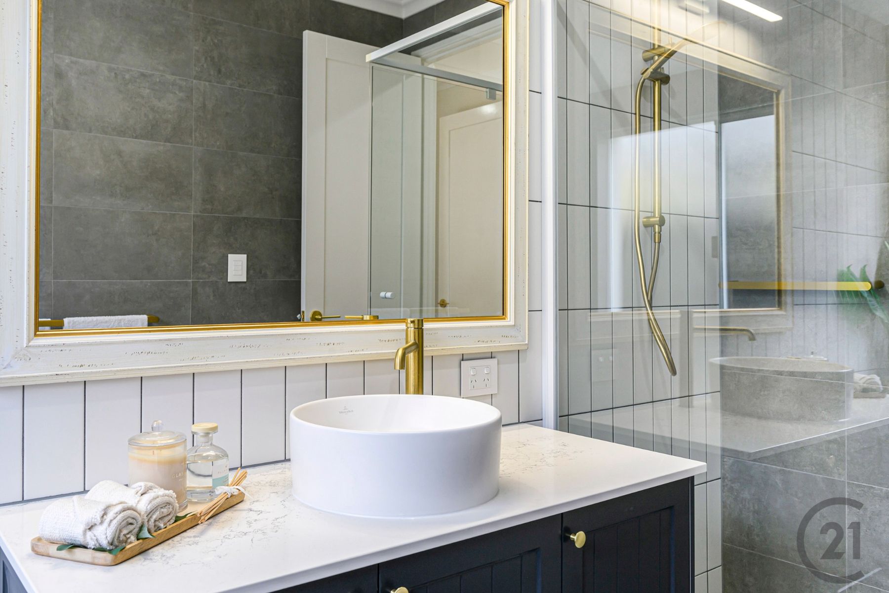Bathroom with charcoal vanity, vessel basin, brass mixer and gold-framed mirror