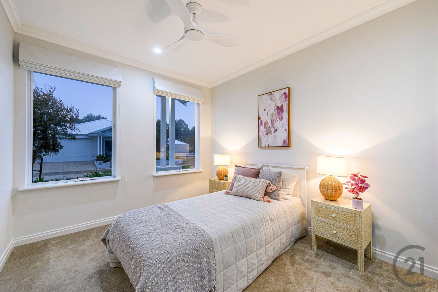 Bedroom with twin windows to the street, rattan lamps and ceiling fan