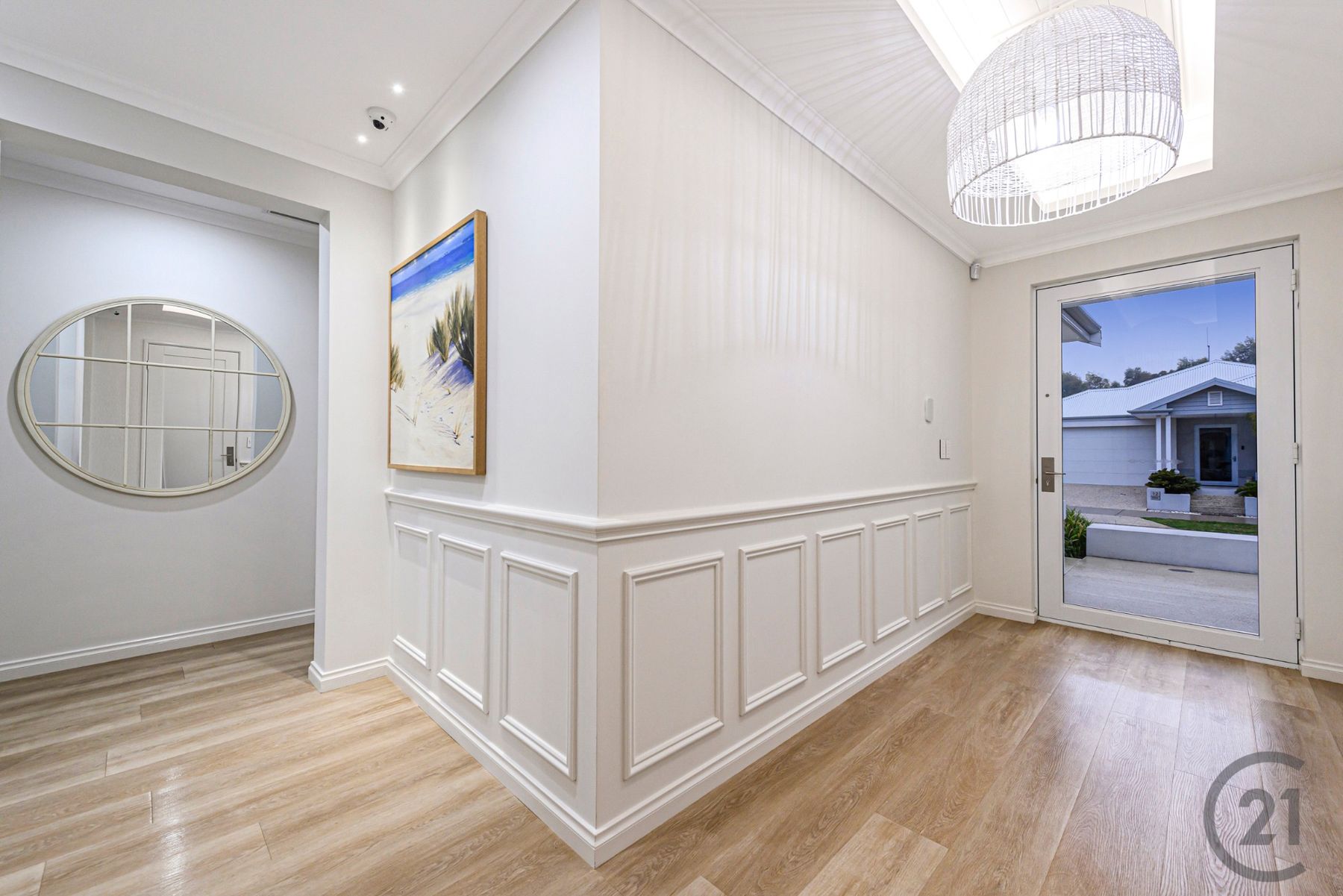 Entry hall with wainscoting, woven pendant, coastal artwork and full-height glass front door