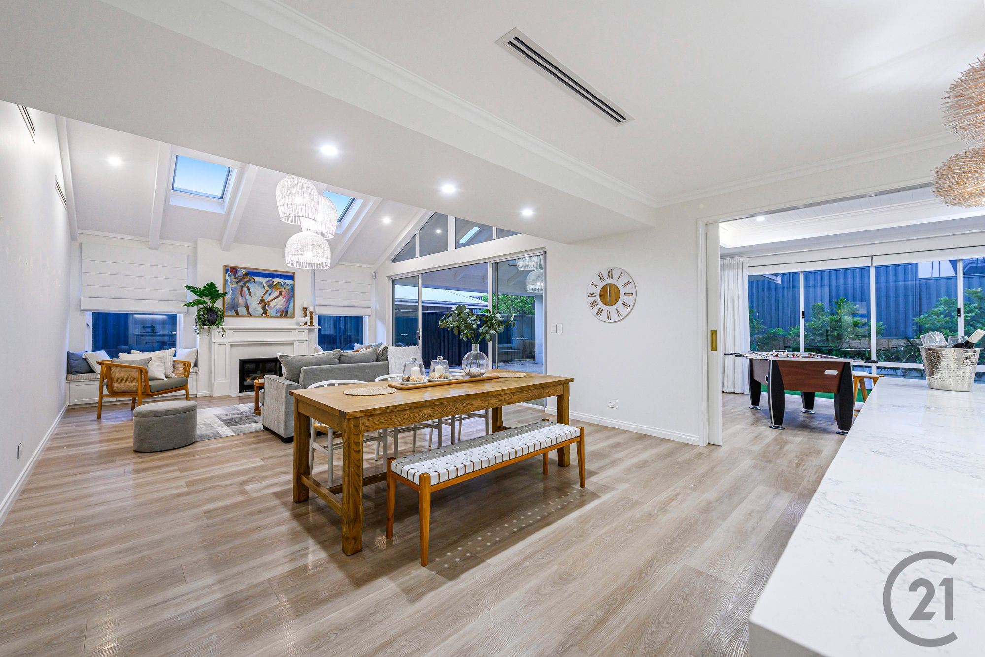 Open-plan living and dining with raked ceiling, skylights, fireplace and the games room beyond