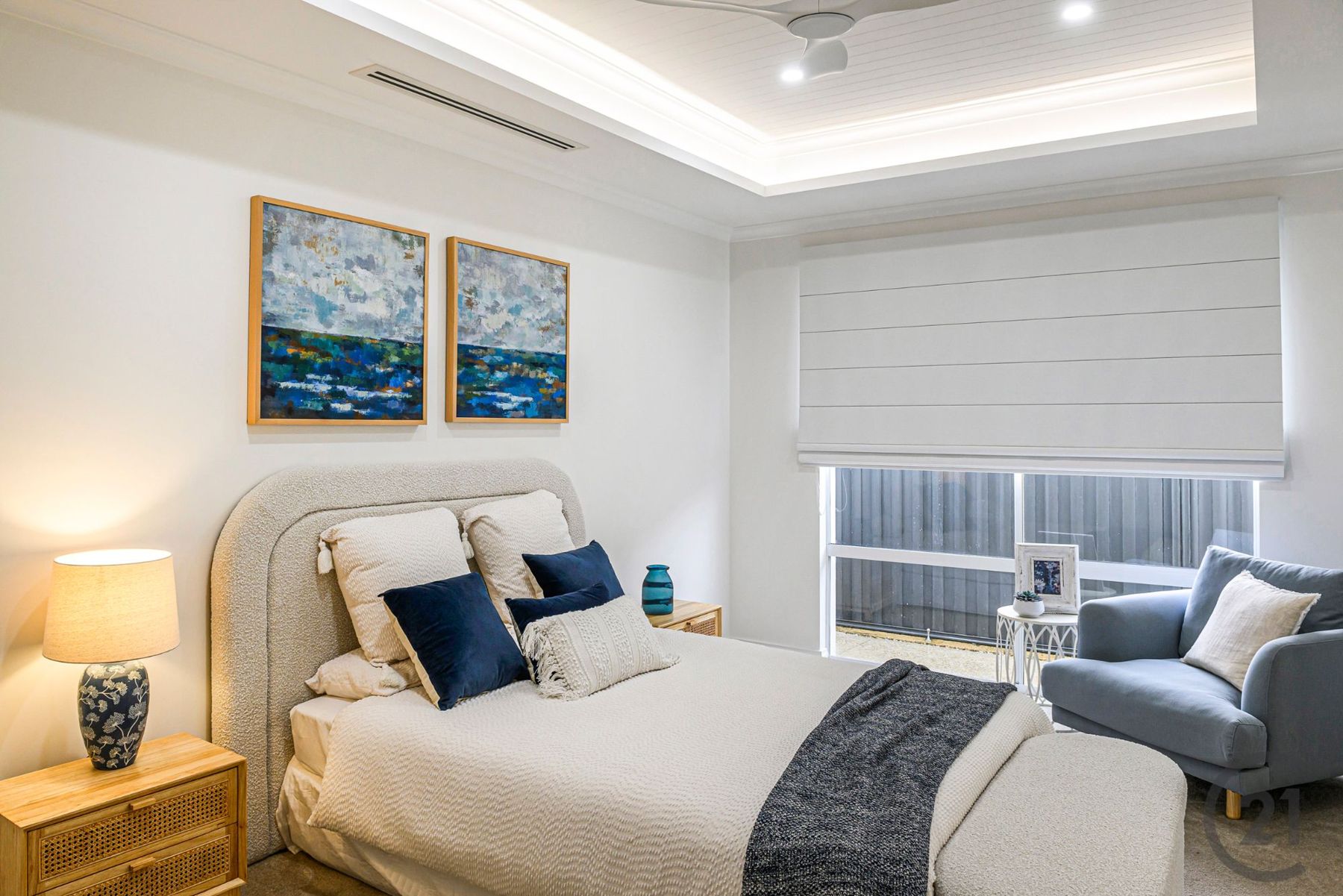 Master bedroom with cove-lit lined ceiling, upholstered bed and armchair by the window