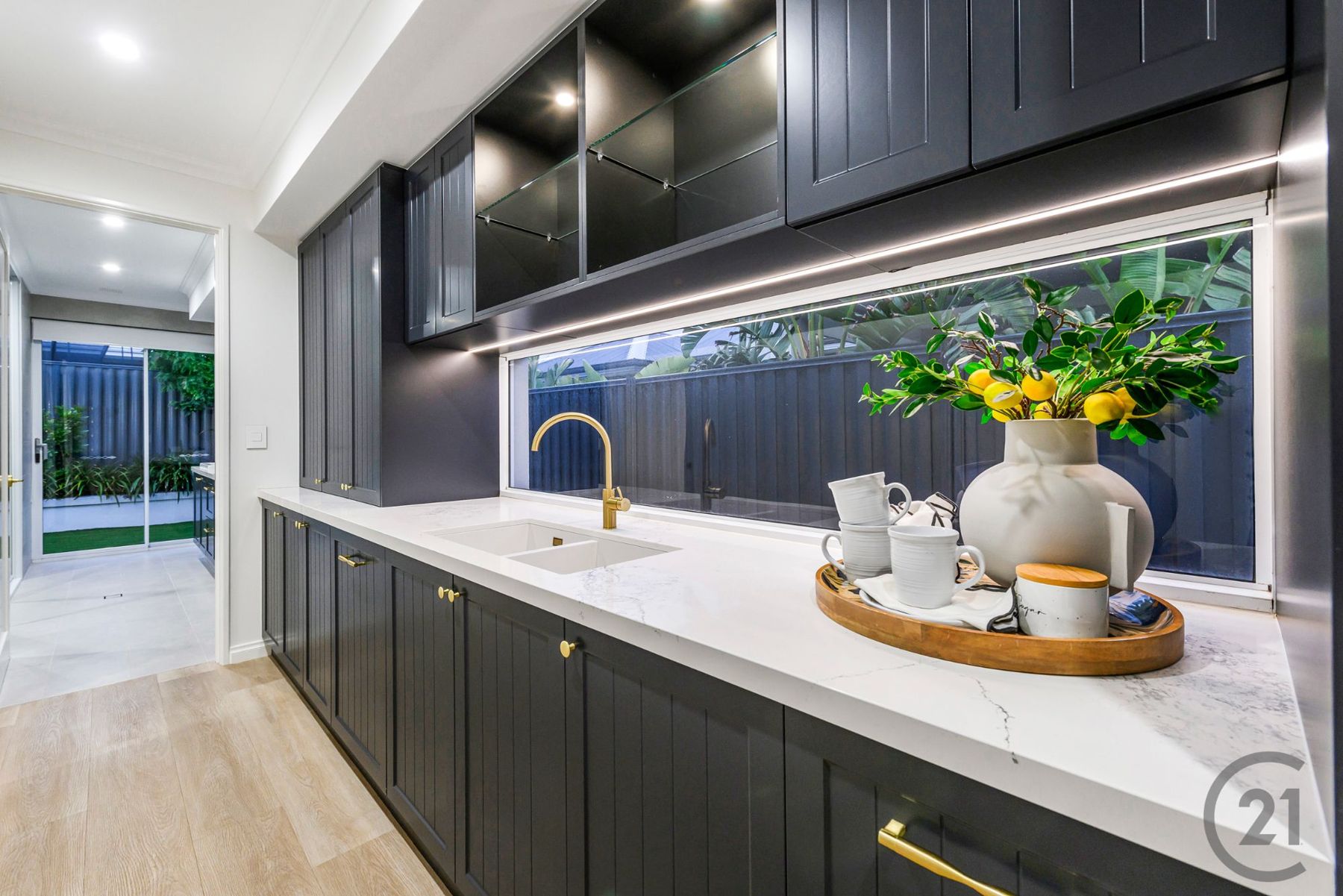 Charcoal scullery with stone bench, brass tapware and long window splashback